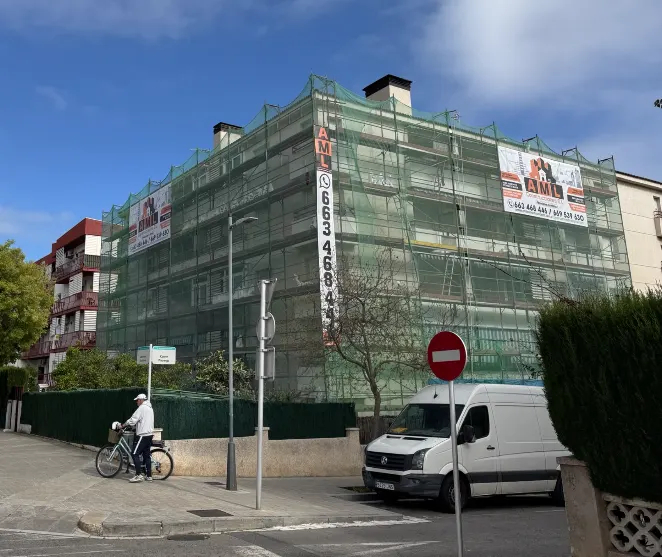 Edificio residencial en rehabilitación con andamio perimetral y malla de protección en Segur de Calafell